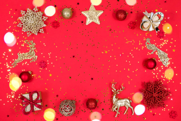 圣诞贺卡。圣诞黄色的彩灯覆盖。金色和红色的圣诞装饰在红色背景上，俯视图，平放。圣诞节的心情。写碑文的地方明信片的基础。图片下载