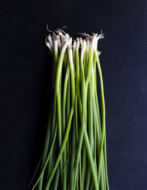 一堆年轻的生态友好的农场洋葱。照片在黑暗的关键。铭文。图片下载