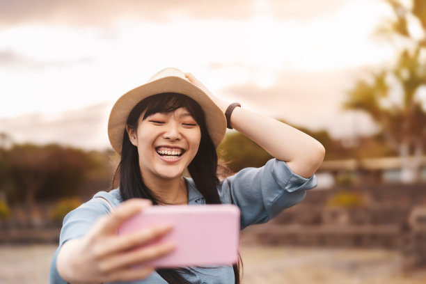 快乐的亚洲女孩在度假期间用手机自拍——中国女性在新趋势的科技应用中享受乐趣——千禧一代和科技社交人士沉迷于这一概念图片下载