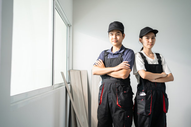 建筑工人下班后对着镜头微笑。亚洲工匠建造或木匠男女戴着蓝色的帽子自信的脸和交叉手臂后修复和翻修房子。图片下载