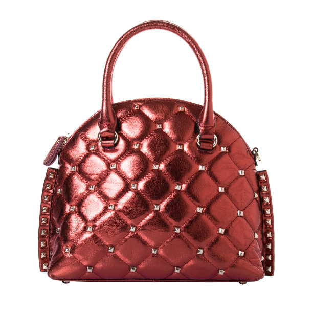 红色手袋由真皮制成，具有金属效果。模型有两个把手，用金铆钉装饰。在白色背景下图片下载