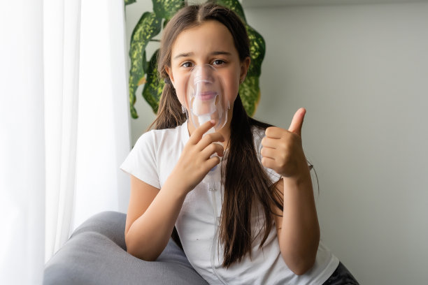 一个患有过敏性哮喘的九岁孩子，一边用间隔吸着药，一边用疲惫的眼睛看着她图片下载