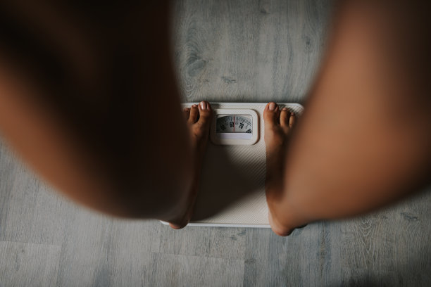 女性赤脚站在体重秤上的特写镜头图片下载