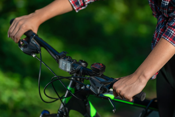 在一个阳光明媚的夏天，一个女人的手放在山地车的把手上图片下载