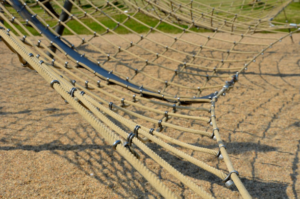绳麻网通过金属不锈钢接头连接在一个木制框架内。这是操场上吸引孩子们的地方。地上的沙子图片下载