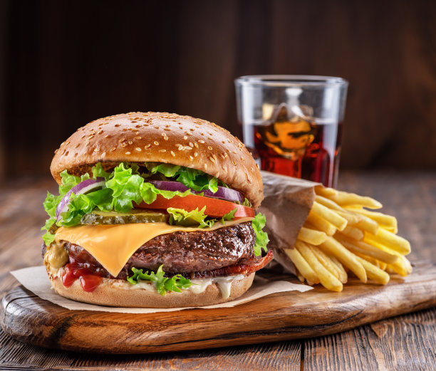 可口的汉堡包、可乐和薯条放在深棕色背景的木桌上。快餐的概念。图片下载