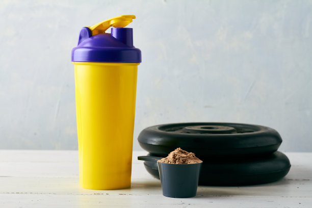 在搅拌器和杠铃附近放一勺蛋白粉图片下载