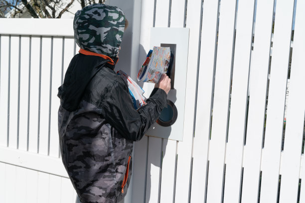 靠向郊区住宅区的私人信箱投递广告小册子赚取微薄收入的小男孩图片下载