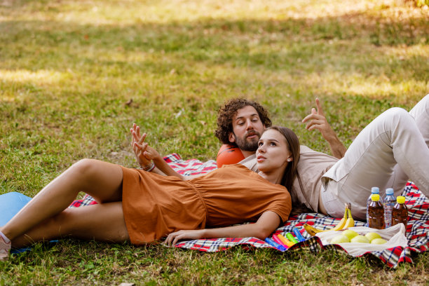 一对幸福的情侣在草地上享受野餐。图片下载