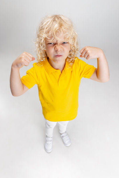 可爱的小卷发学前班男孩有乐趣，玩孤立在灯光工作室背景。图片下载