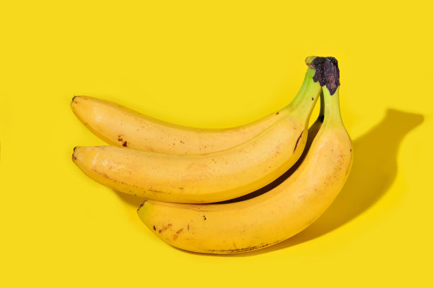 新鲜香蕉被隔离在工作室的黄色背景上图片下载