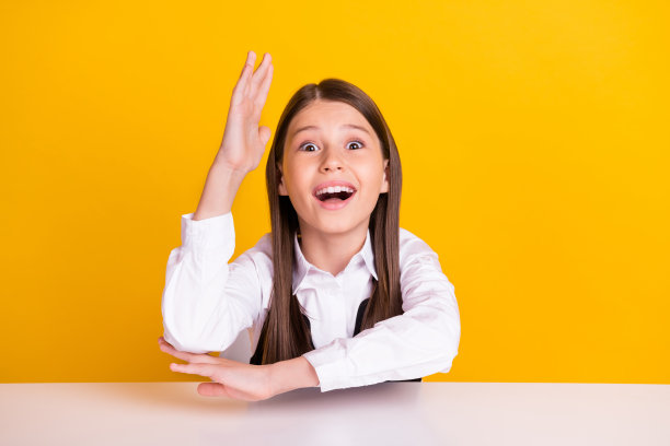 小印象深刻的女孩穿着白色衬衫在黄色背景上学习的照片图片下载