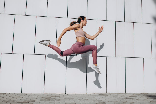 侧面的形象，年轻苗条的运动白人妇女工作，做健身，瑜伽在城市的街道。图片下载