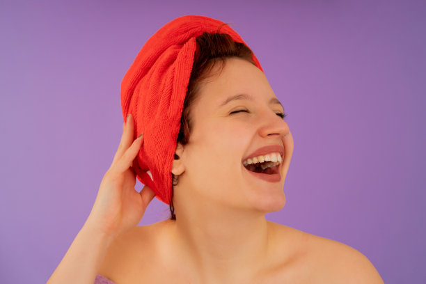 年轻女子头戴毛巾面带微笑。图片下载