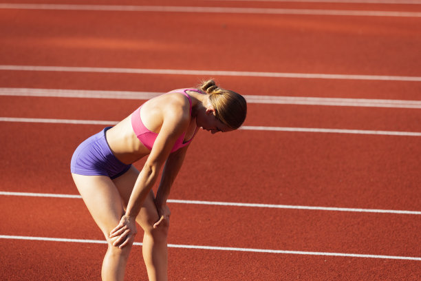 一名白人女性，女运动员，跑步者在公共体育场、运动场或户外运动场训练。夏天的运动游戏。图片下载