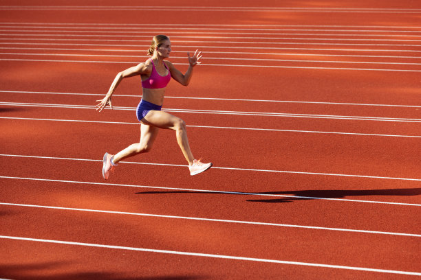 一名白人女性，女运动员，跑步者在公共体育场、运动场或户外运动场训练。夏天的运动游戏。图片下载