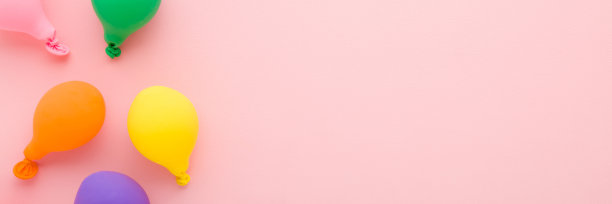 彩色气球上浅粉色的桌子背景。柔和的颜色。特写镜头。宽横幅。为鼓舞人心的，积极的文本，可爱的引用或谚语留出空间，为好心情。自顶向下的观点。图片下载