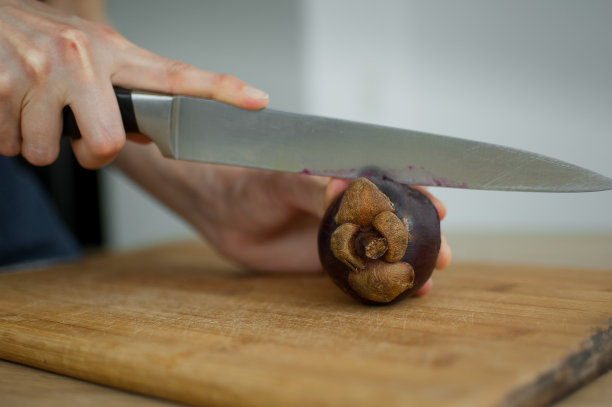 女人们正用刀在切好的木板上切着熟透了的山竹。异域水果，健康饮食理念图片下载