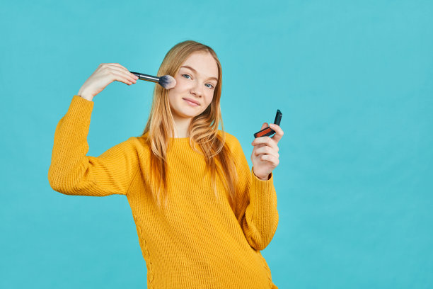 带着发带的快乐女孩拿着化妆刷。腮红或眼影。年轻皮肤的化妆品。隐藏的皮肤问题。图片下载