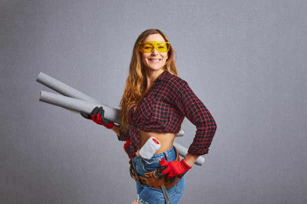漂亮的年轻女人拿着墙纸卷。专业女职工手拿墙纸和滚筒。快乐女孩正在准备自己动手修理或粉刷。图片下载