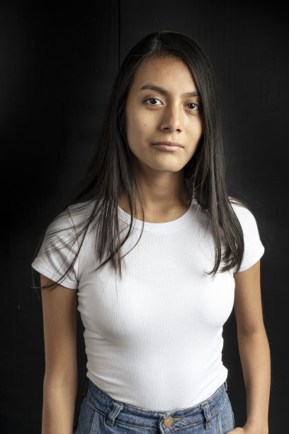 一个美丽的拉丁女人的中垂直肖像，黑色的头发和白色的t恤，她的手臂在她的身边。图片下载