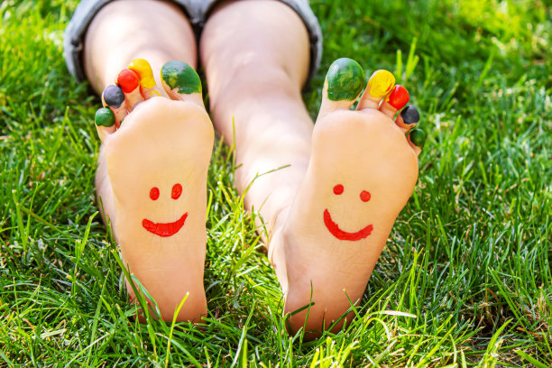 孩子们的脚画着图案微笑在绿草地上。有选择性的重点。图片下载