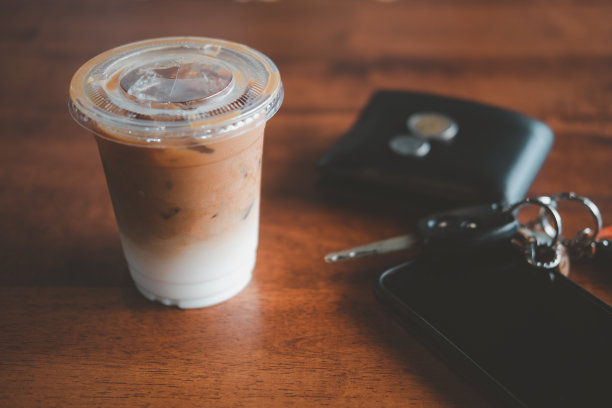 近距离观看放在桌上的冰咖啡，旁边的钱包，车钥匙和手机在咖啡馆。的办公桌上图片下载