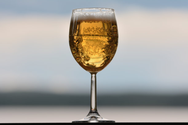 一杯啤酒，泡沫和倒挂的天空。背景是模糊的，没有聚焦的夜空和湖泊图片下载