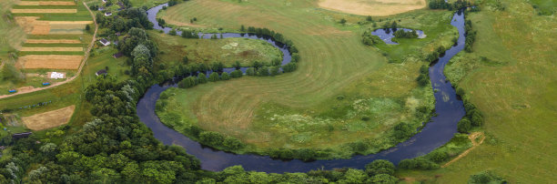 绿色田野中蜿蜒河流的空中景观，从无人机上俯瞰美丽的自然背景，带有复制空间的季节性夏季景观。图片下载
