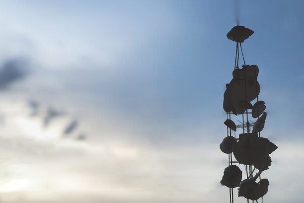 蓝天背景的贝壳剪影挂式移动装饰，在傍晚日落和复制空间的柔和聚焦，感受孤独，在度假中平静放松。图片下载