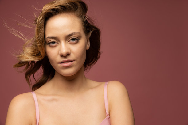特写的年轻美丽的女人在棕色的背景粉红色内衣。图片下载