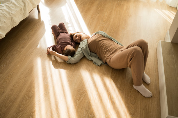 一个女人躺在木地板上，她的女儿患有唐氏综合症图片下载