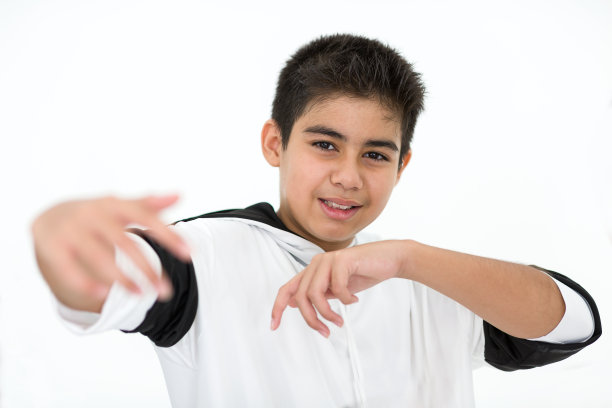 在白色背景的舞蹈中心，微笑的小男孩在课堂上做嘻哈运动的肖像图片下载