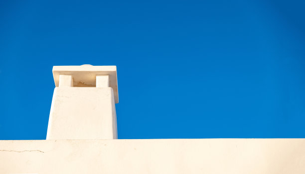 屋顶上的烟囱背景是蓝天。米洛斯岛，普拉卡乔拉，基克拉迪斯希腊。图片下载