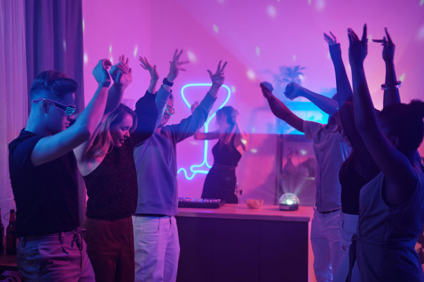 年轻的跨文化朋友们穿着休闲装，一边跳舞一边举起手臂图片下载