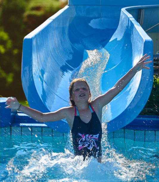 漂亮的小女孩滑在水滑入跳水池。水上乐园里有趣的儿童乐园。假期的概念图片下载