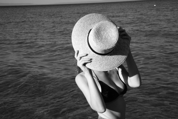 黑白照片上的女人穿着比基尼，手里拿着草帽图片下载