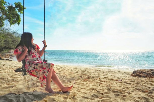 一个女人坐在沙滩上的吊床上图片下载