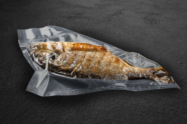 真空袋装烤黄金鱼，背景黑色。可以吃了。图片下载