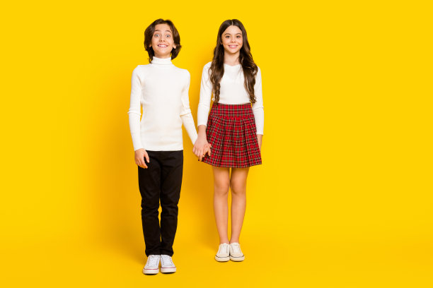 孩子们穿着休闲服装微笑的全身尺寸照片，在鲜艳的黄色背景下孤立图片下载
