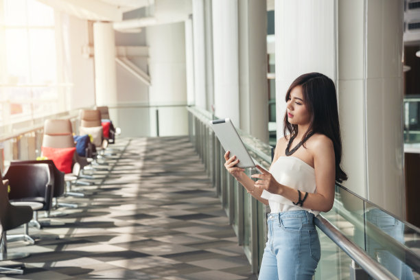 亚洲工作妇女白衬衫蓝牛仔裤衣服黑色长发站使用平板图片下载