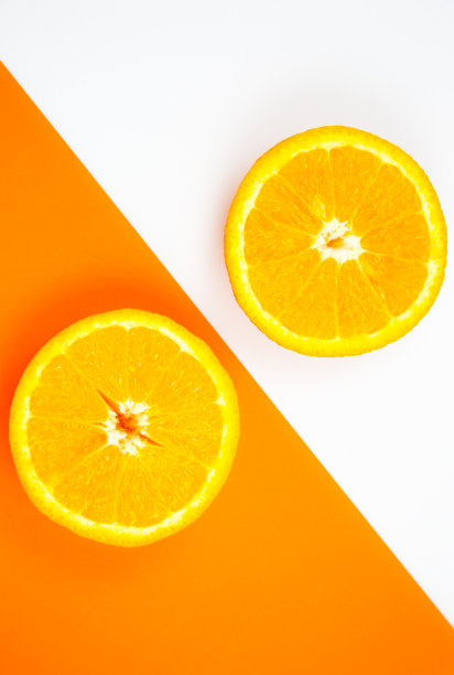 橙色水果在白色和橙色背景上的特写照片。柑橘切成两半，内部，宏观视图。极简主义，原创和创意的形象。美丽的自然墙纸。图片下载