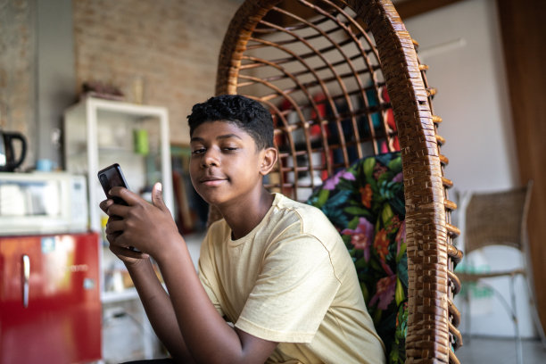 一名十几岁的男孩在家里使用智能手机图片下载