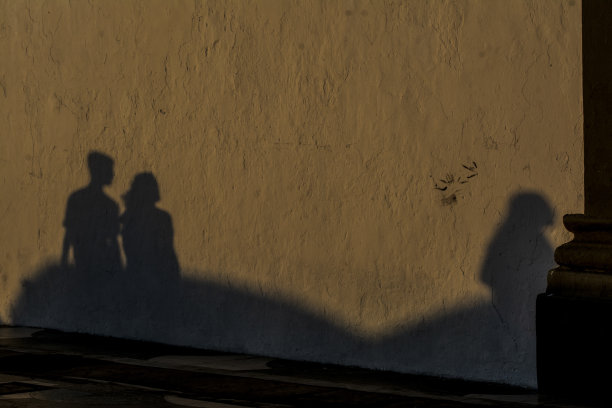 在夕阳的余晖中，人们的影子投射在墙上。图片下载