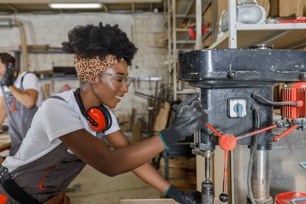 年轻夫妇在木工制造与钻床工作的木工照片。图片下载