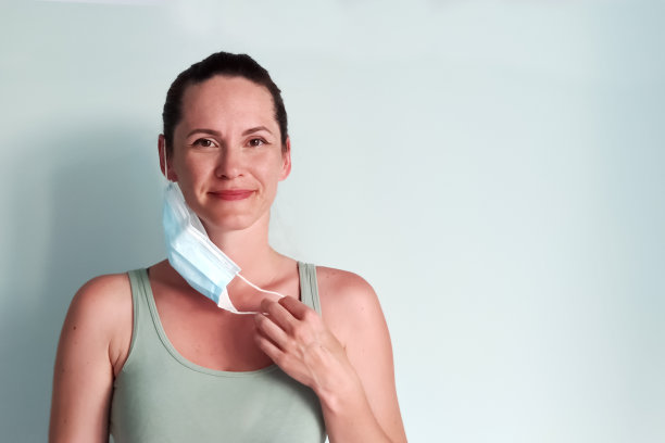 年轻女子愉快地摘下医用口罩。图片下载