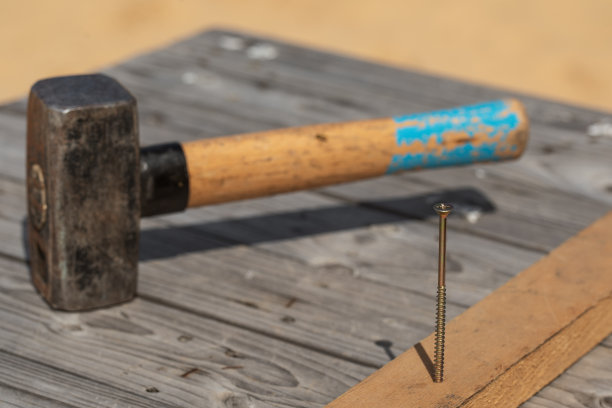 把锤子和钉子钉在旧木制工作台上图片下载