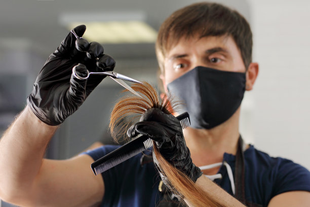 一个戴着黑色丁腈手套的理发师为一个女孩剪长发。图片下载