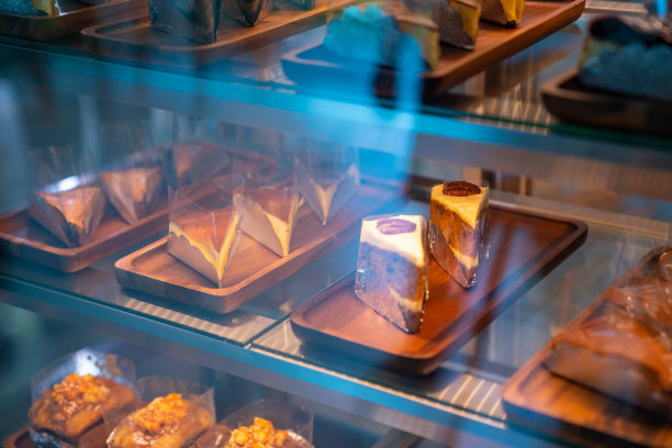 一名亚洲女咖啡店员工正在把蛋糕放进烘焙店的冰箱里图片下载