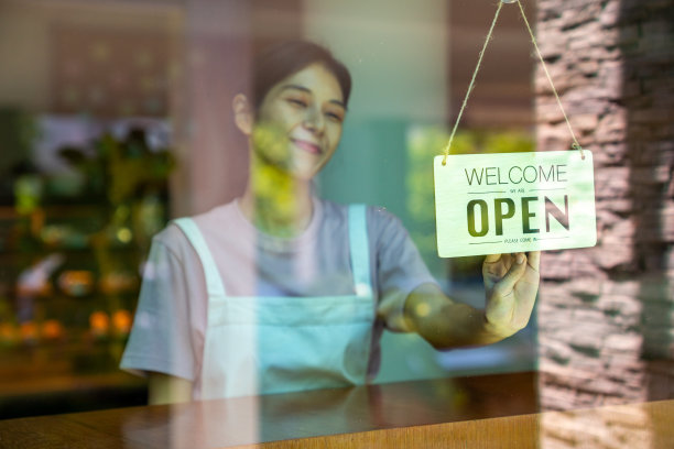 亚洲女服务员在咖啡店的门上挂着开门的牌子图片下载